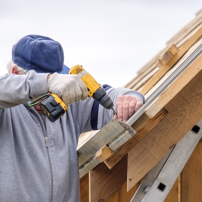 A roofer is drilling the underlayment for a new roof.